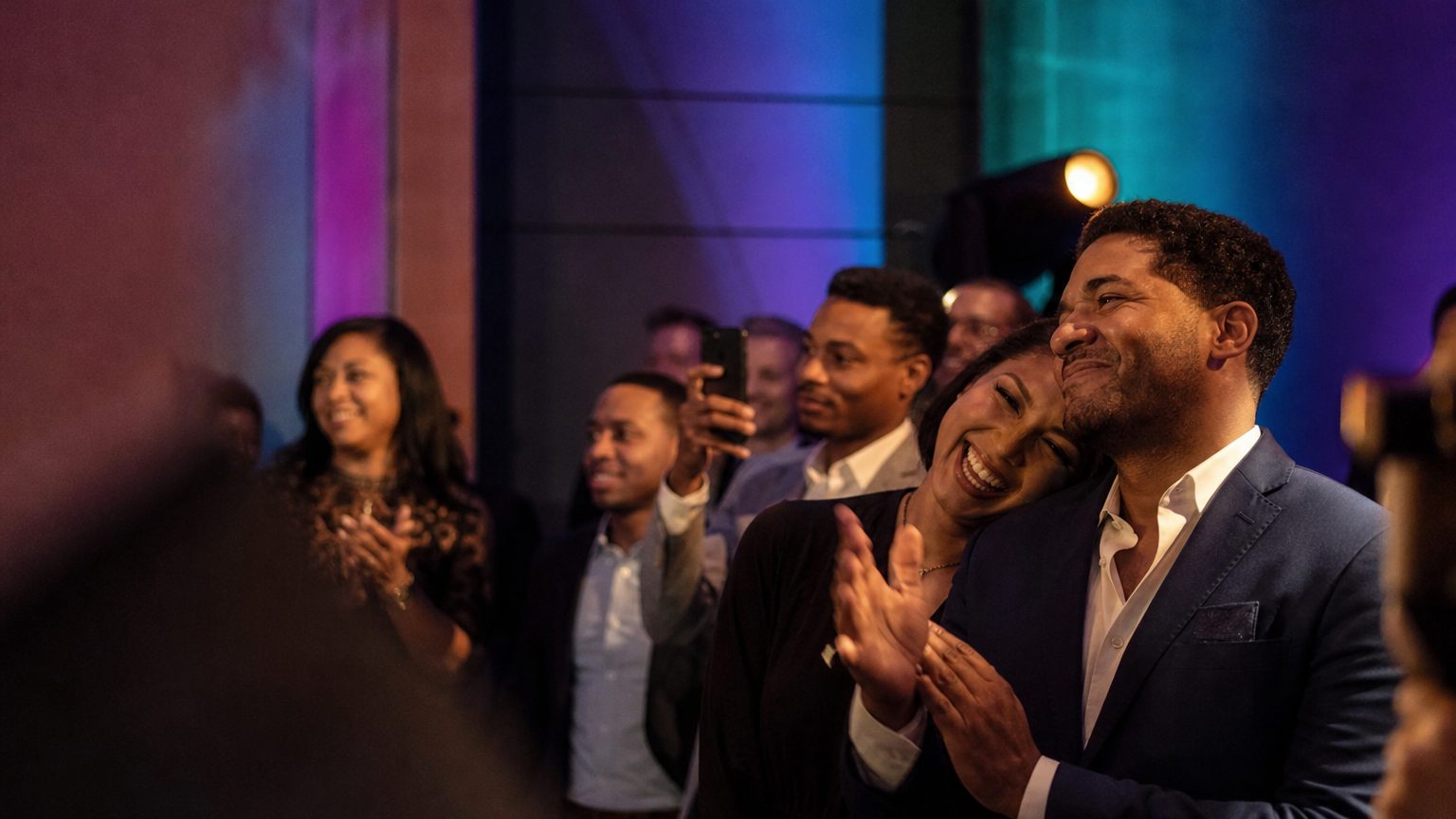 Attendees watching and clapping near a small stage
