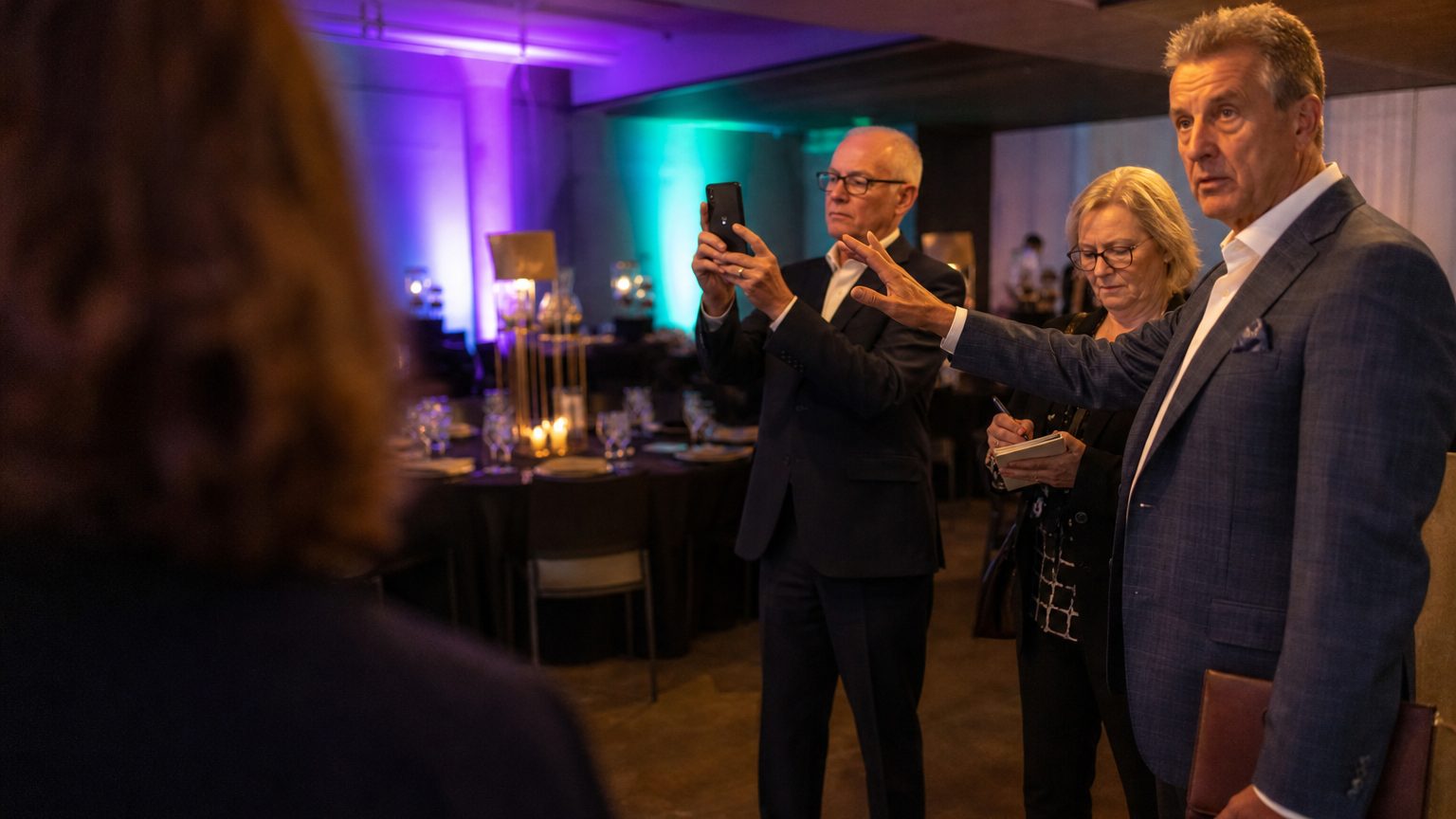A venue manager gesturing across a function space to two corporate planners