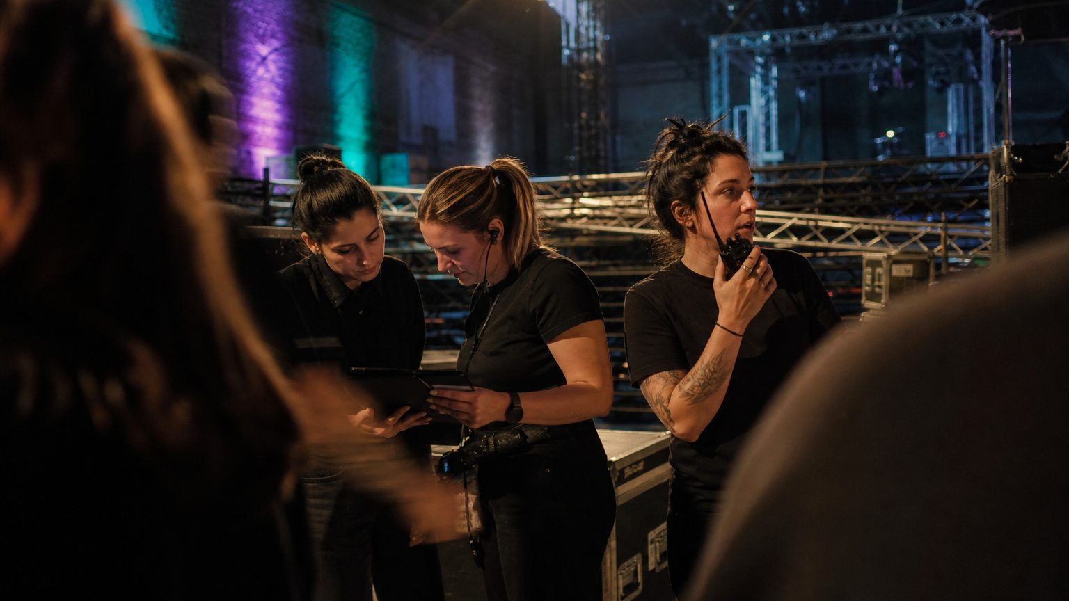 Two crew in black checking a rigging plot on a tablet while a third talks into a radio