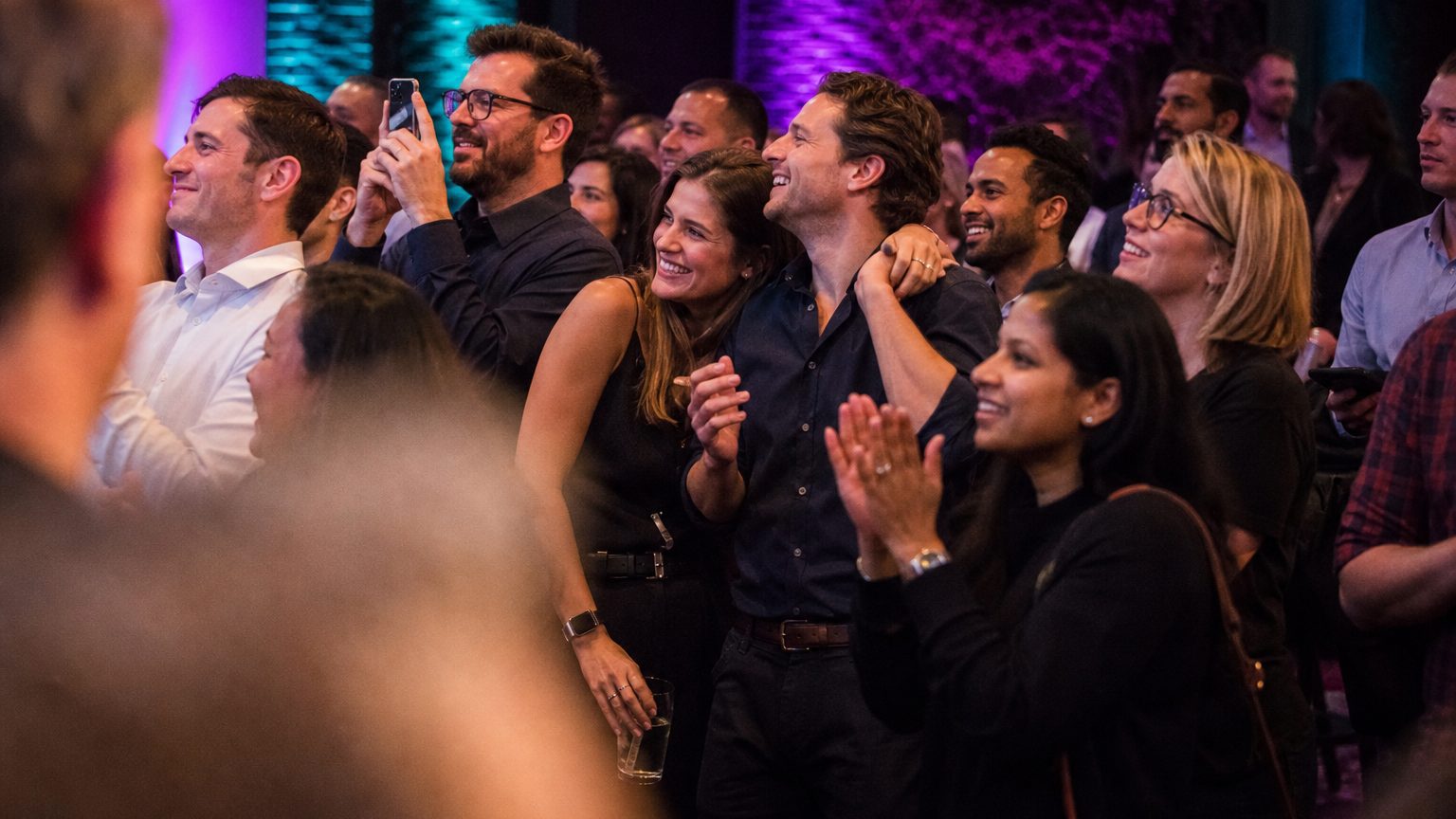 Attendees watching and clapping near a small stage