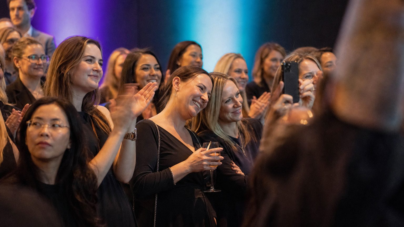 Attendees watching and clapping near a small stage
