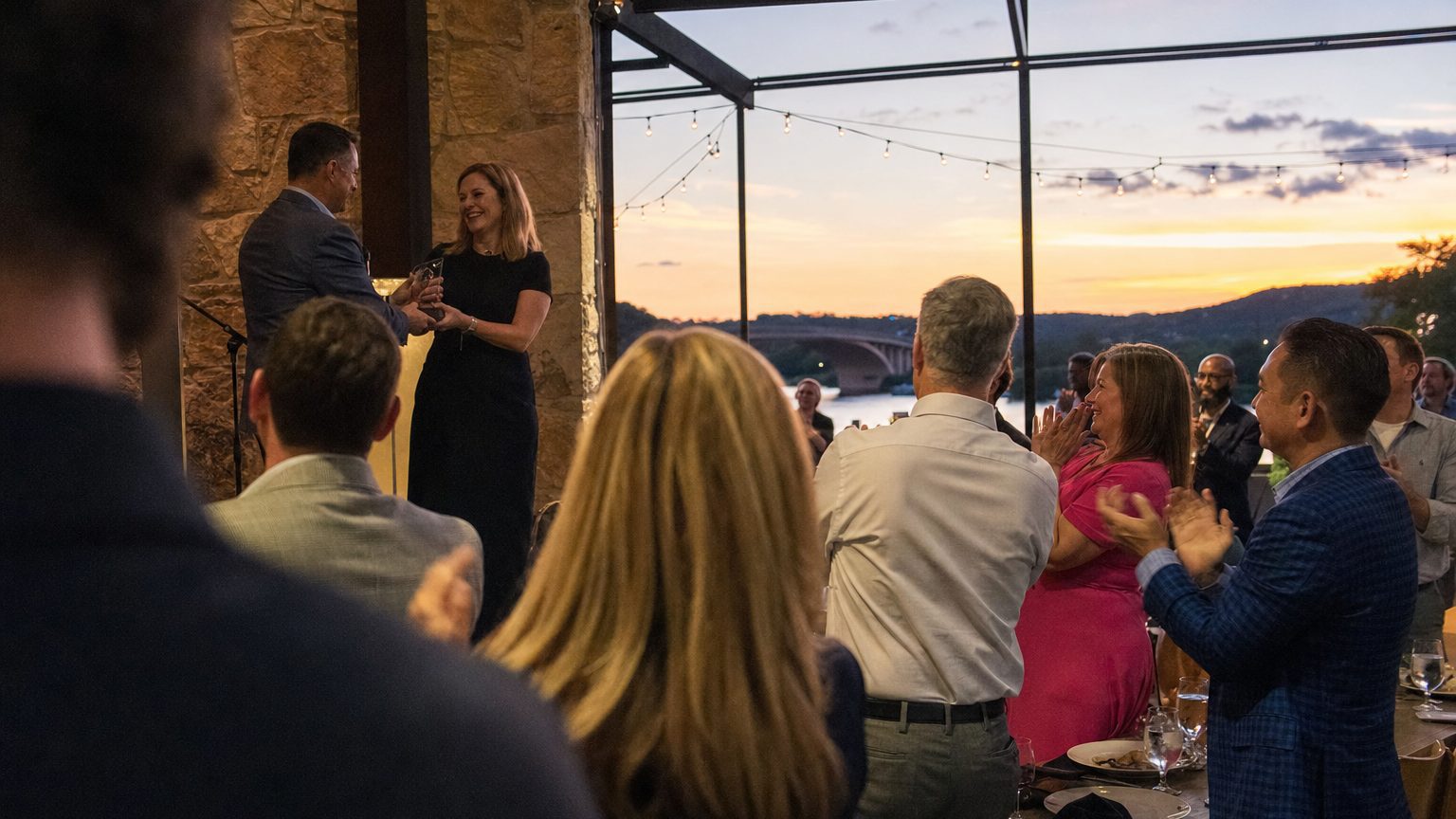 A venue manager gesturing across a function space to two corporate planners