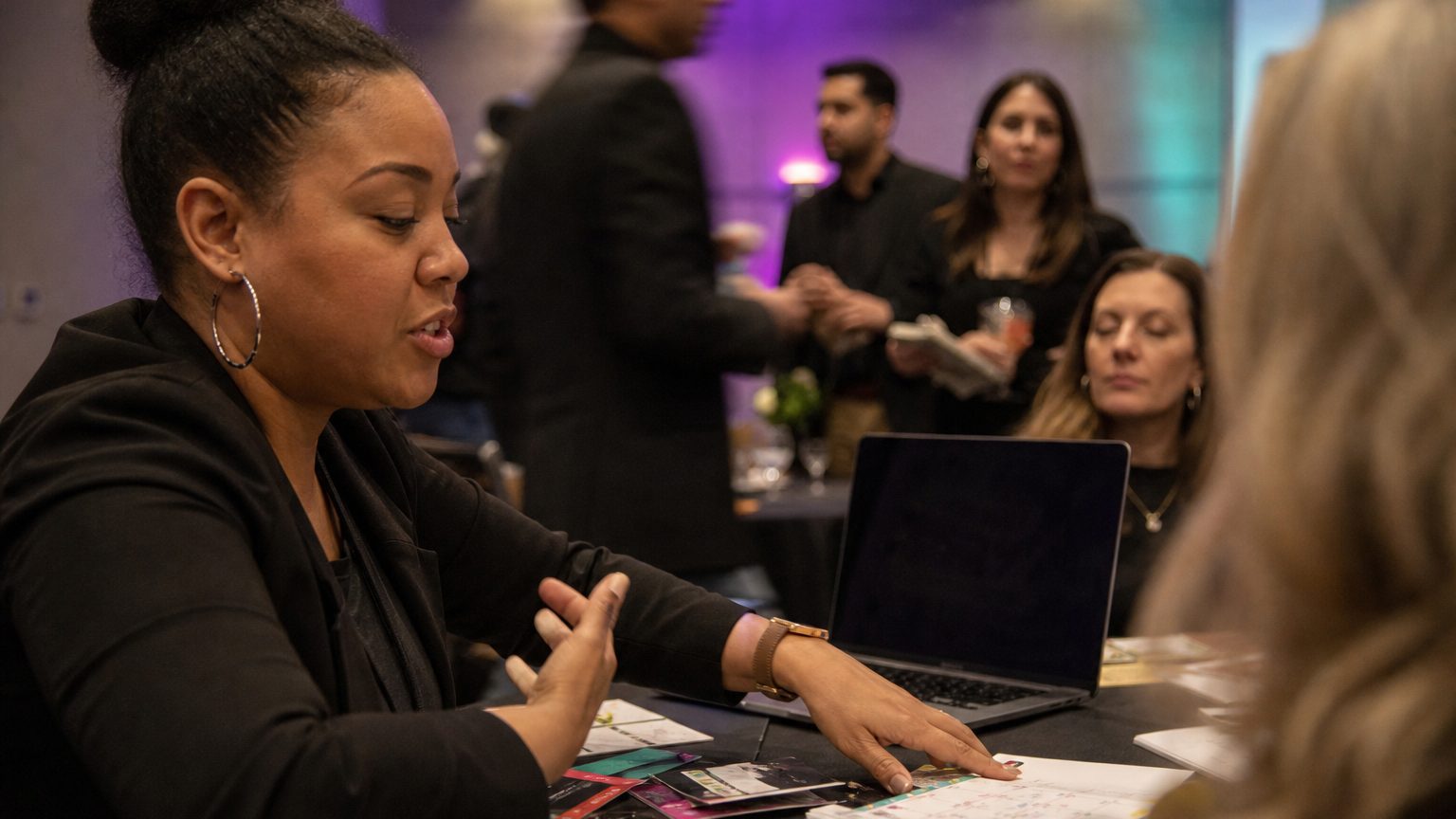 Close-up of a planner’s hands arranging colorful event materials on a table, with a laptop open beside them and a cale