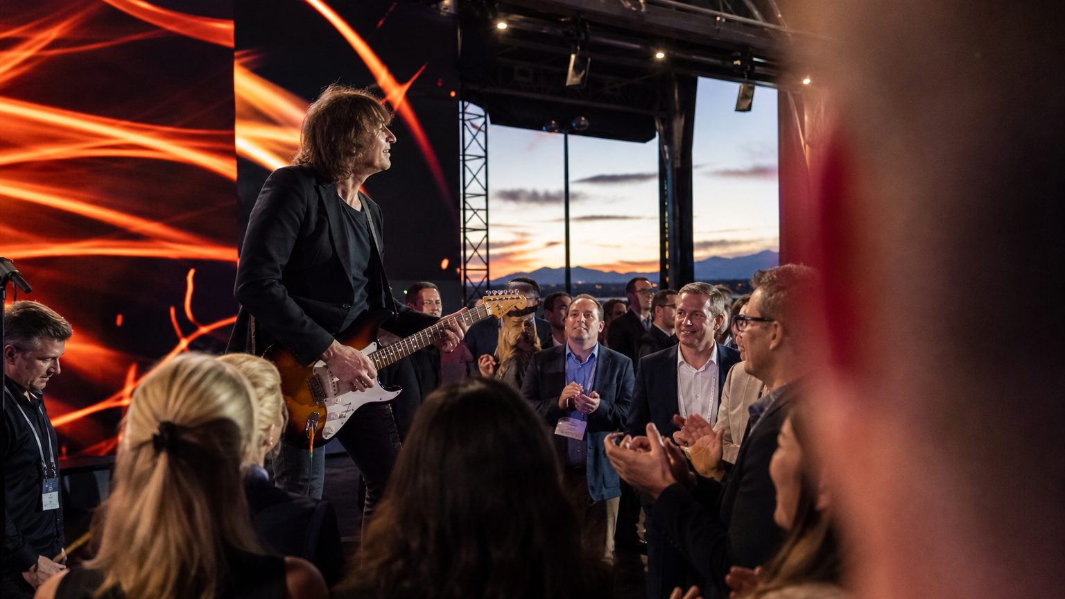 A venue manager gesturing across a function space to two corporate planners