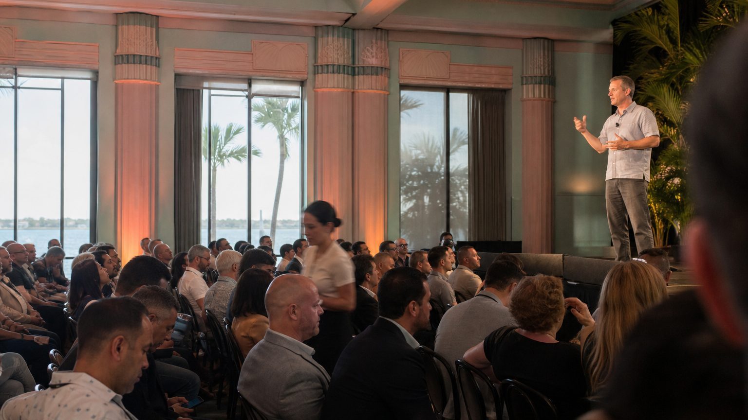 A venue manager gesturing across a function space to two corporate planners