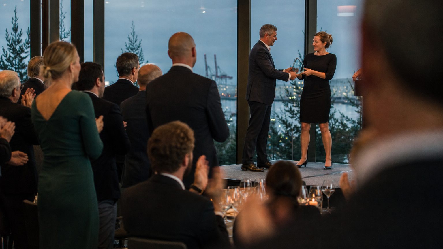 A venue manager gesturing across a function space to two corporate planners