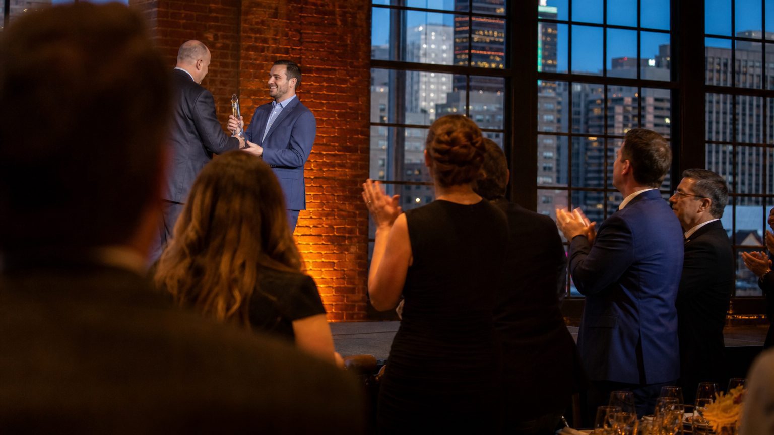 Two corporate event planners across a hotel meeting-room table mid-discussion