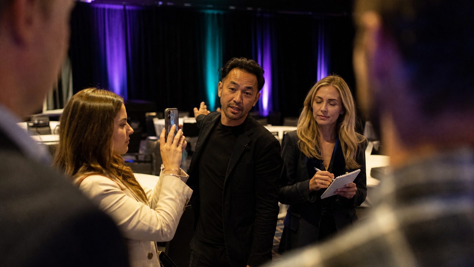 A venue manager gesturing across a function space to two corporate planners