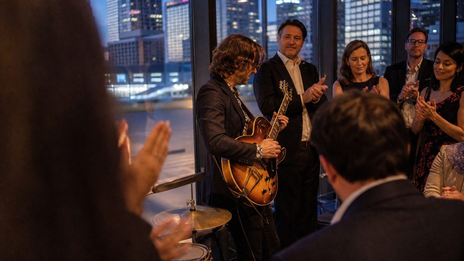 A venue manager gesturing across a function space to two corporate planners