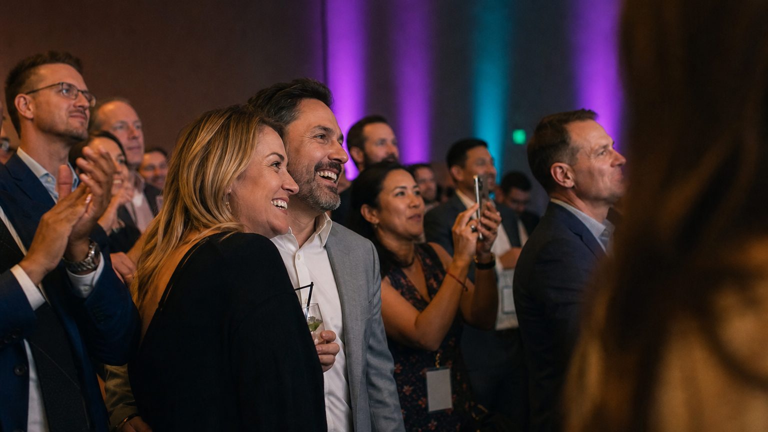 Attendees watching and clapping near a small stage