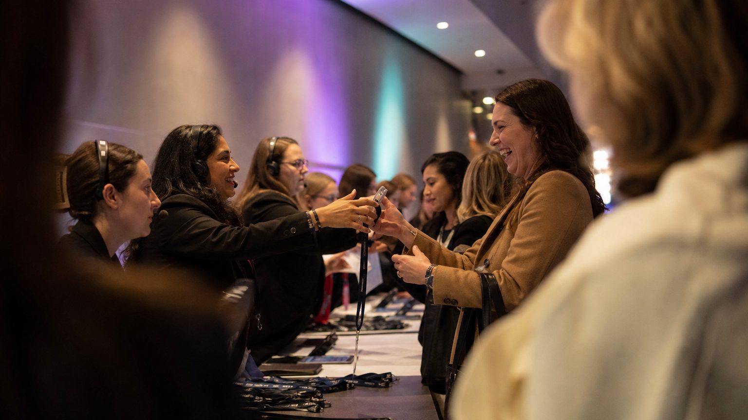 Attendees collecting badges from staff at a busy registration desk