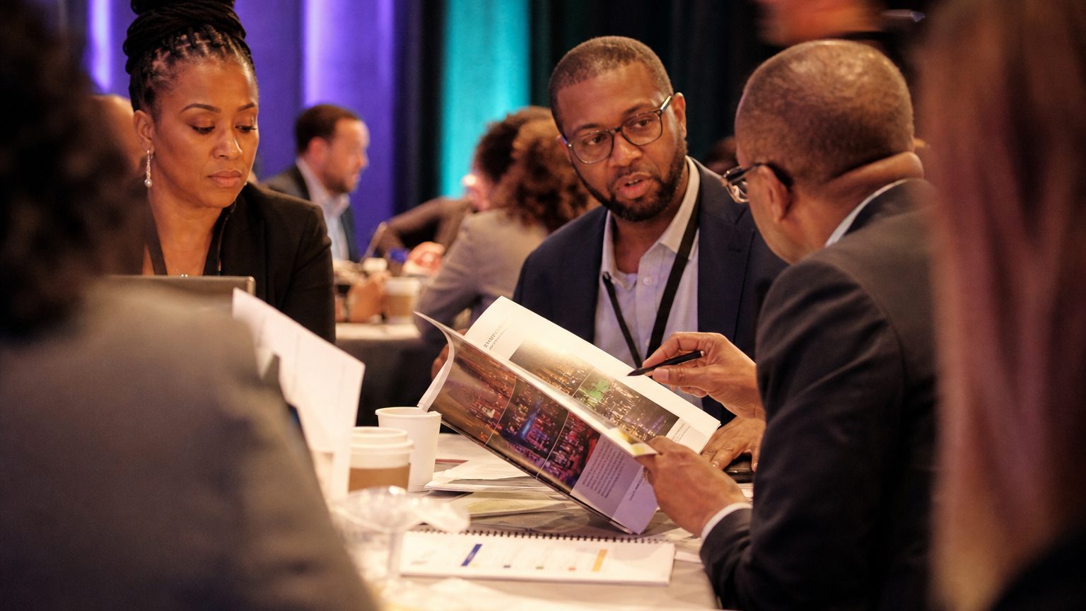 Close-up of a person in business attire flipping through a colorful event proposal booklet, highlighting key benefit s