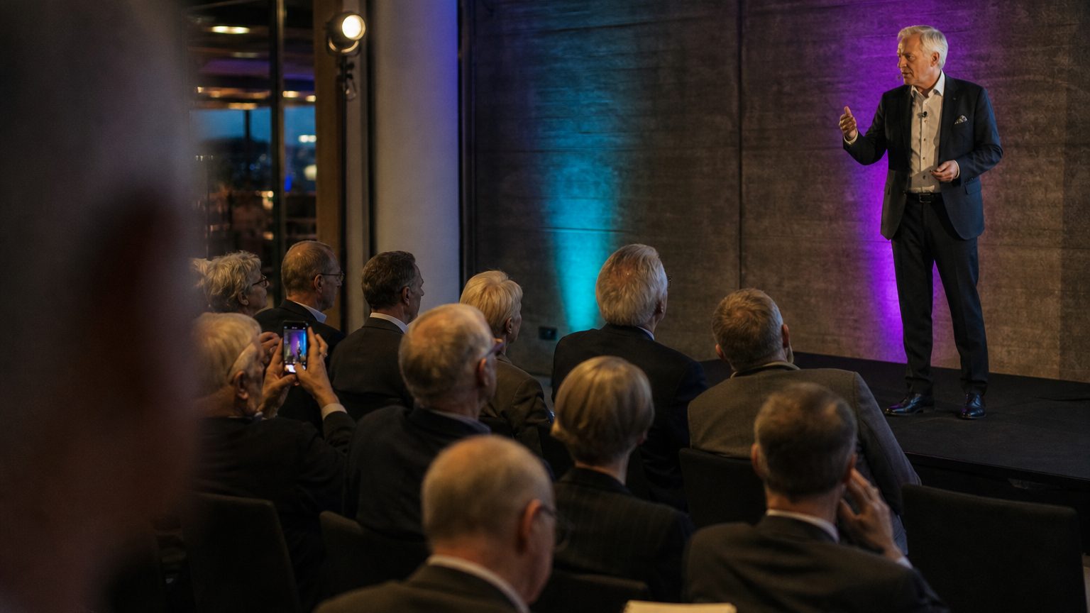 A speaker mid-gesture on a low stage