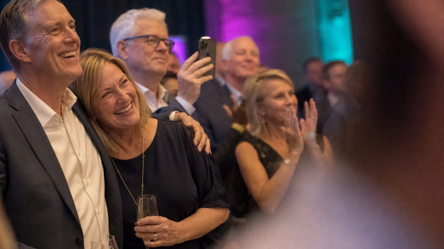 Attendees watching and clapping near a small stage