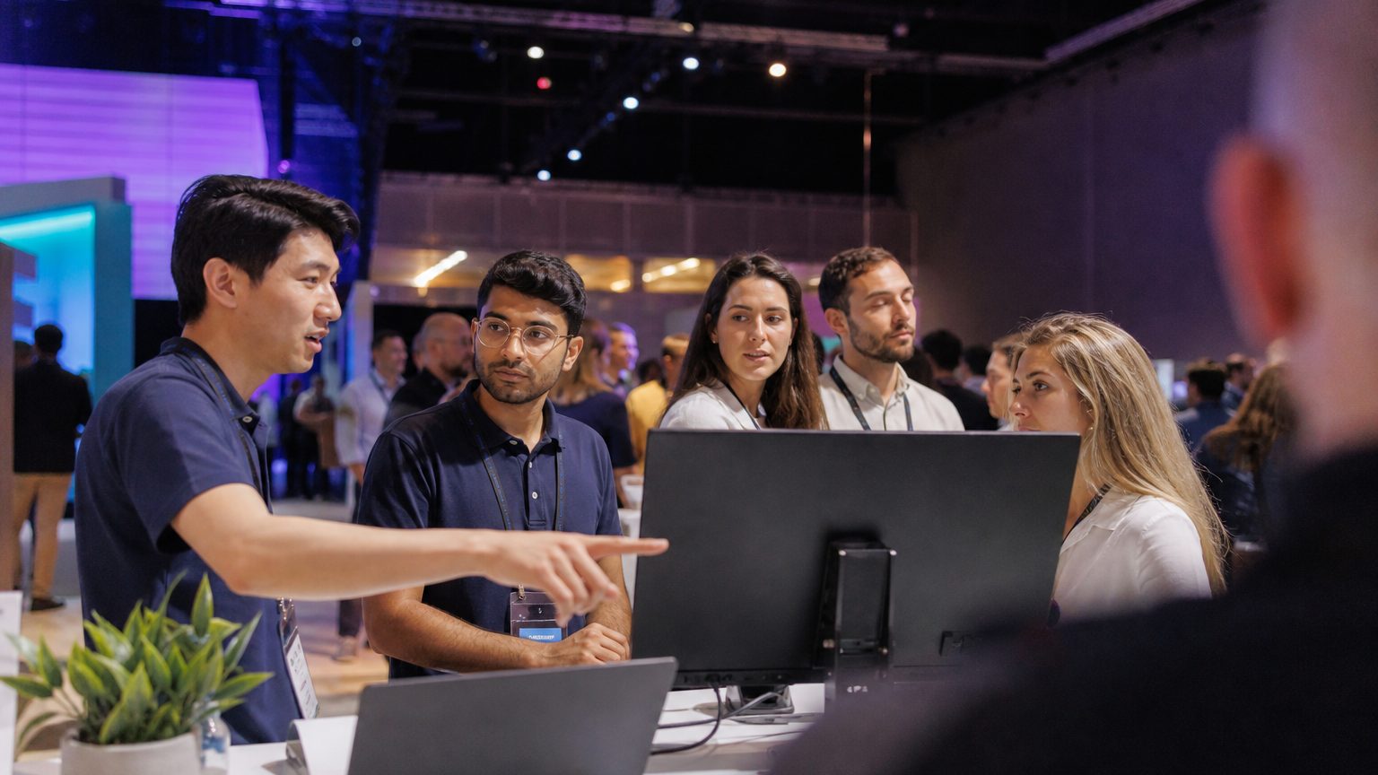 Booth staff demonstrating a product to visitors on a busy trade show floor