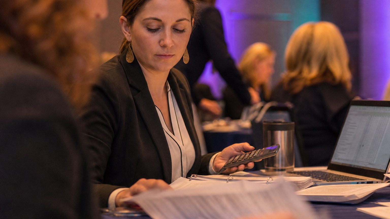Close-up of an event planner at a desk, reviewing detailed tax documents and compliance forms for a sales incentive tr