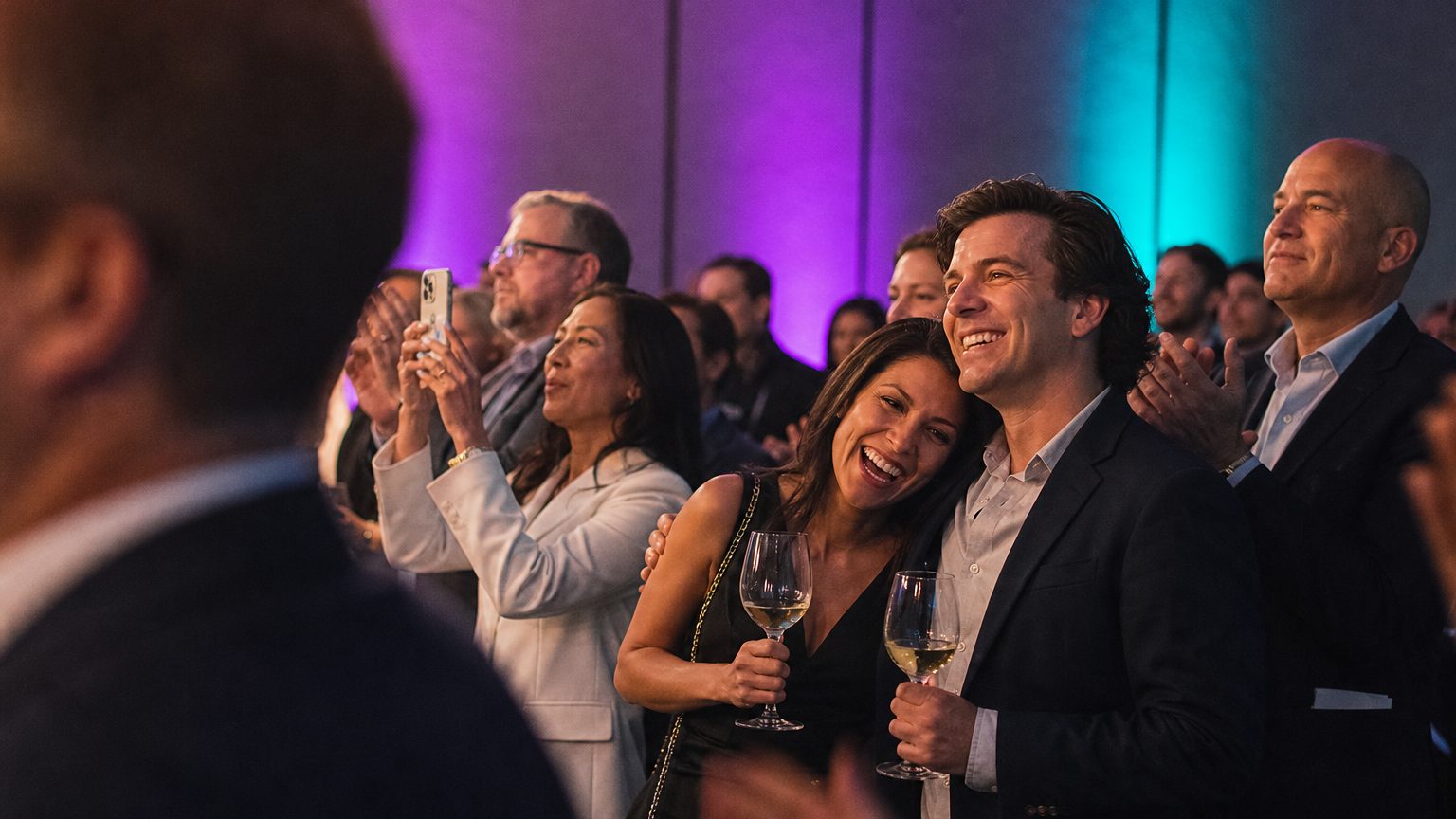 Attendees watching and clapping near a small stage