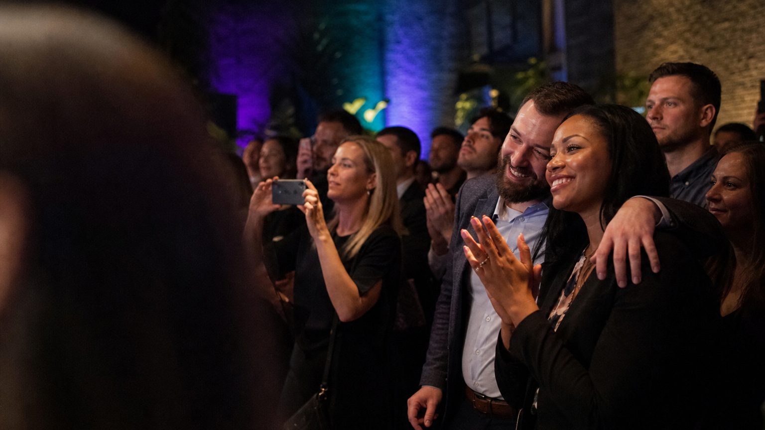 Attendees watching and clapping near a small stage