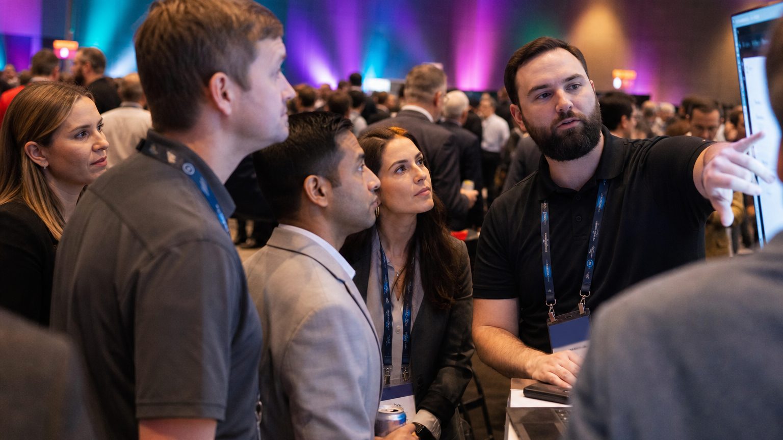 A crowd of attendees engaged with staff at a busy exhibit stand