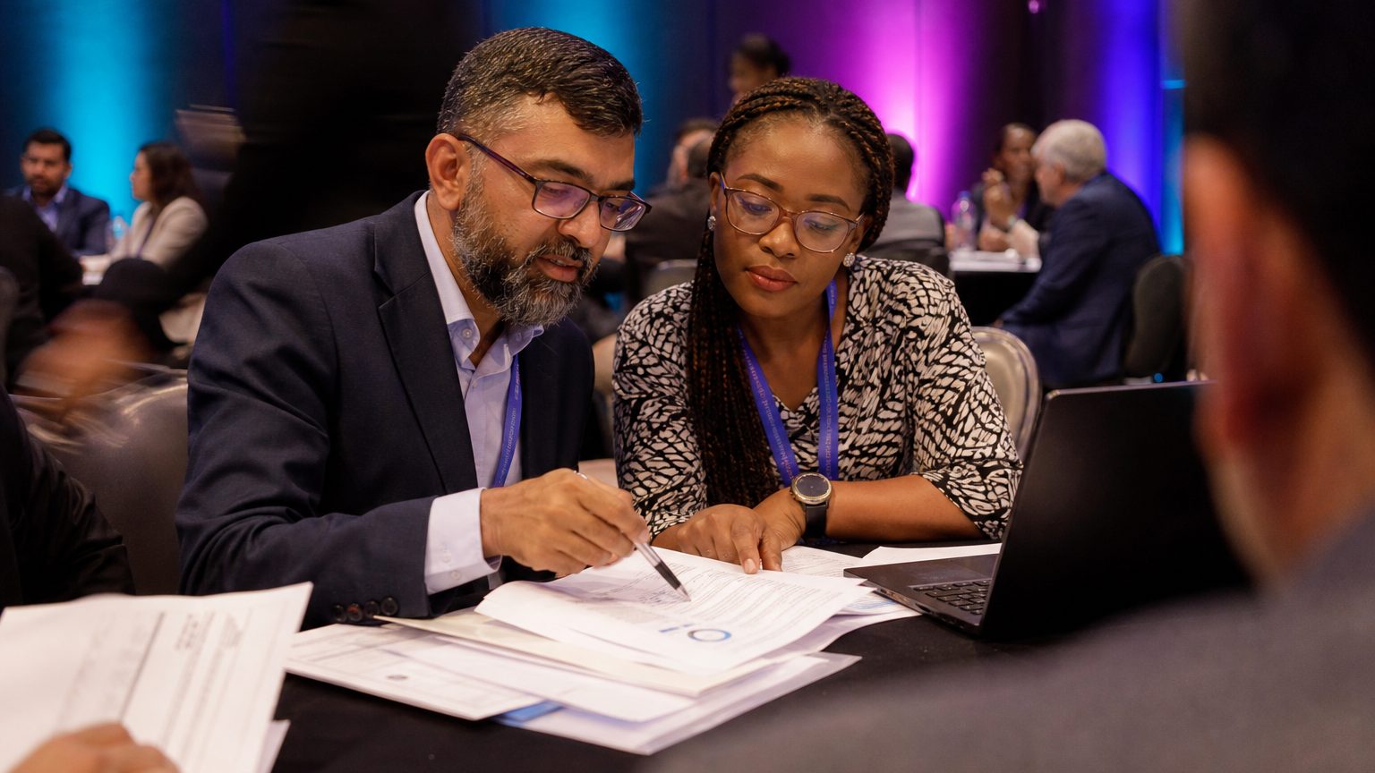 Close-up of a finance manager and a procurement officer reviewing printed budget sheets and contract documents togethe